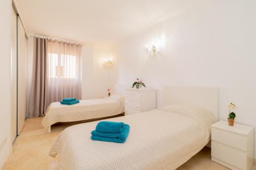 Dos camas en una habitación blanca con toallas azules. en La Recoleta Mediterranea, en Torrevieja