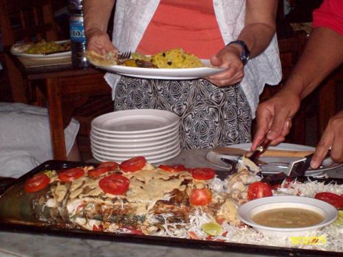a person holding a plate of food on a table at Langi Langi Beach Bungalows in Nungwi