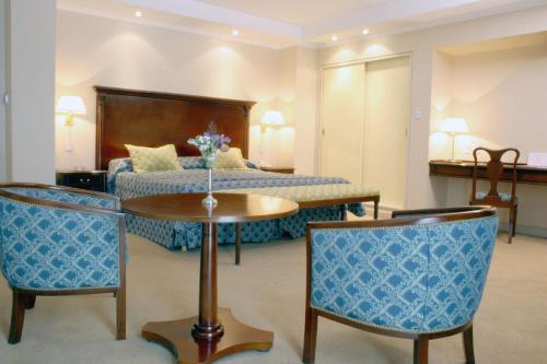 ein Hotelzimmer mit einem Bett, einem Tisch und Stühlen in der Unterkunft Provincial Plaza Hotel in Salta