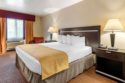 ein Hotelzimmer mit einem großen Bett und einem Schreibtisch in der Unterkunft Best Western Luxury Inn in Tracy