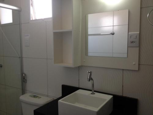 uma casa de banho com um lavatório, um WC e um espelho. em Pousada Porto das Dunas em Aquiraz