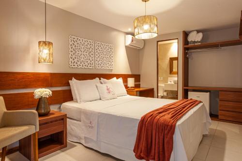 a bedroom with a bed and a chair and a mirror at Charme da Vila Suítes in Porto De Galinhas
