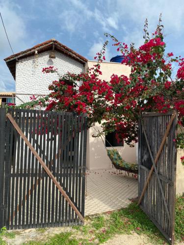 a black fence with red flowers in front of a house at Chalé do Coqueiro in Luis Correia