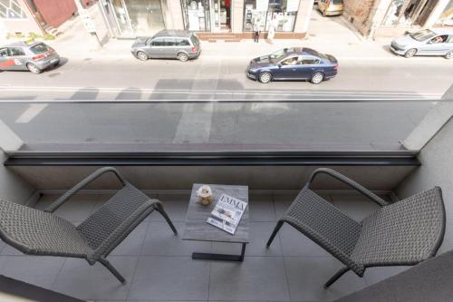 two chairs and a table on a balcony with cars at Hany Sweet in Niš