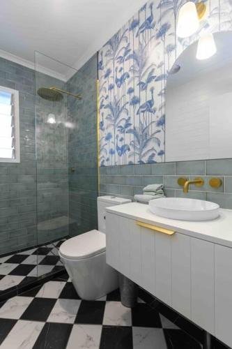 a bathroom with a toilet and a sink and a mirror at Pandanus Place - with Bicycles in Port Douglas