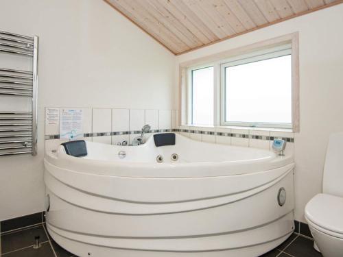 a white bath tub in a bathroom with a toilet at Three-Bedroom Holiday home in Hemmet 74 in Falen