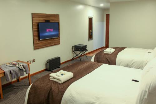 Habitación de hotel con 2 camas y TV de pantalla plana. en Hotel Unu, en Huancayo