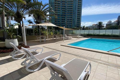 a pool with lounge chairs and a swimming pool at Hi Surf Beachfront Resort Apartments OFFICIAL SITE in Gold Coast