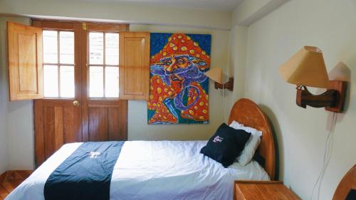 a bedroom with a bed and a painting on the wall at Colores Hotel Apu-Linli in Pisac