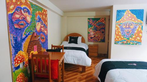 a room with two beds and paintings on the wall at Colores Hotel Apu-Linli in Pisac