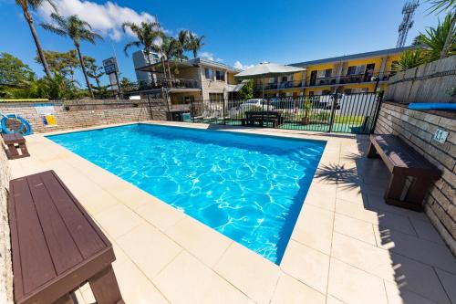 a swimming pool with a bench in front of a building at Forster Motor Inn in Forster