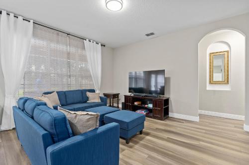 a living room with a blue couch and a tv at WindsorHills Villa Pool Resort Amenities Minutes to Disney in Orlando