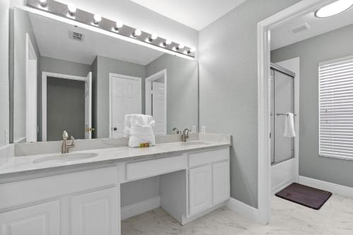 a white bathroom with a sink and a mirror at WindsorHills Villa Pool Resort Amenities Minutes to Disney in Orlando