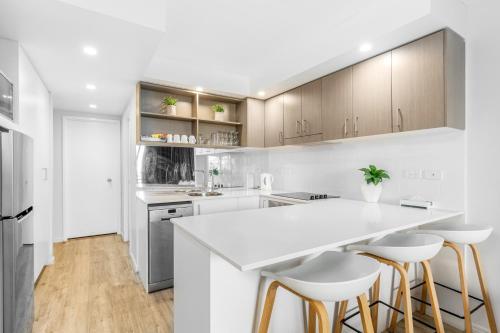 a kitchen with a white counter and bar stools at Bayview Tower in Yeppoon