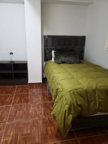 una camera con un letto verde e pavimenti in legno di Apartamento familiar entero Cusco x5 a Cuzco