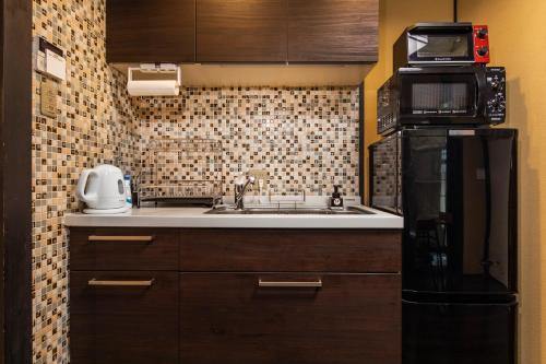 a small kitchen with a sink and a microwave at Tofukuji Sakura & Tsuki in Kyoto