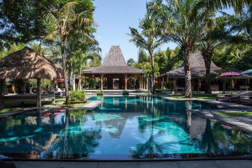a swimming pool at a resort with palm trees at The BK Village in Canggu
