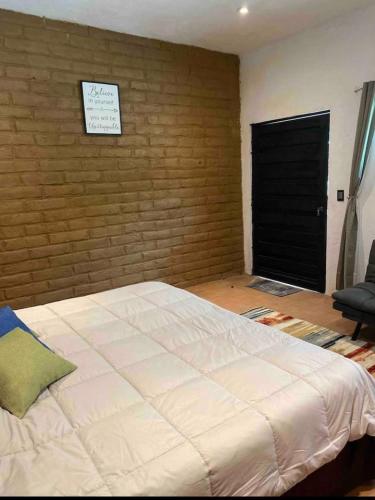 a bedroom with a large bed and a brick wall at SUITE EL GUAYABO en Tepoztlán in Tepoztlán