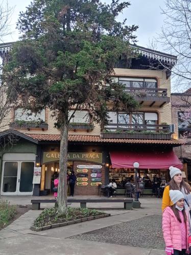 a woman and two children walking in front of a building at Amplo e Central Apartamento 3 Quartos in Gramado