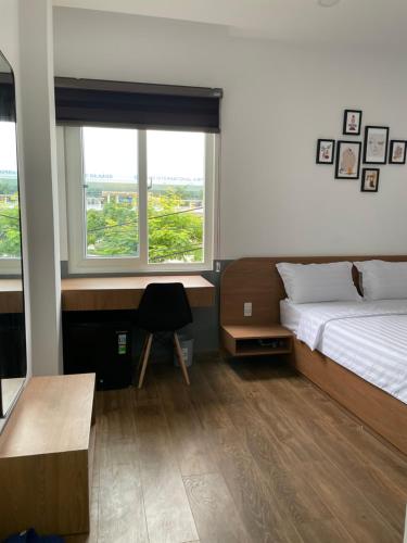 a bedroom with a bed and a desk and two windows at Airport homestay in Danang