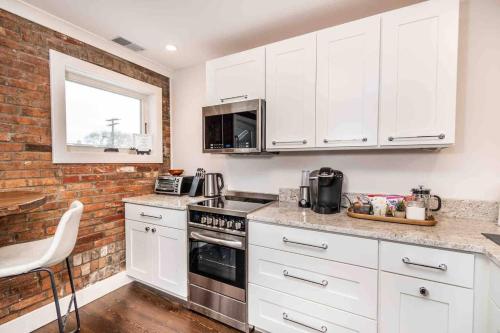 una cocina con armarios blancos y una pared de ladrillo en Luxury Design Focused, Detroit Themed Apt Near Downtown In the art District en Detroit