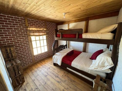 Refugio Aralar EcoLodge في Toca: غرفة نوم بسريرين بطابقين وجدار من الطوب
