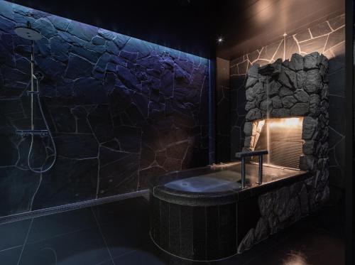 a bathroom with a stone wall and a tub at moksa in Kyoto