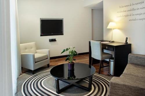a living room with a couch and a table and a desk at Movich Casa del Alferez in Cali