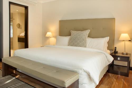 a bedroom with a large white bed and two lamps at Movich Casa del Alferez in Cali