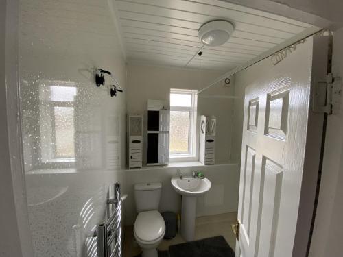 Baño blanco con aseo y lavamanos en Private Lounge and Double Room en Kilwinning