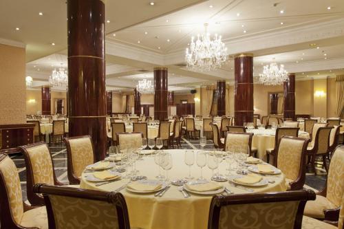 a dining room with a table and chairs and chandeliers at Hotel Alameda Palace in Salamanca