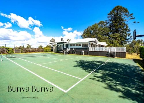 a tennis court with a house in the background at Bunya Bunya Luxury Estate Toowoomba set over 2 acres with Tennis Court in Toowoomba