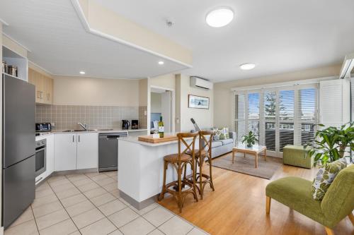 una cucina a pianta aperta e un soggiorno con bancone e sedie di Salt - 2brm apartment with Spa bath and Ocean Views a Kingscliff