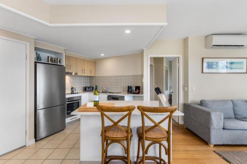 a kitchen with a refrigerator and two bar stools at Salt - 2brm apartment with Spa bath and Ocean Views in Kingscliff