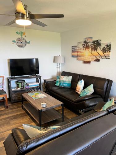 a living room with a leather couch and a table at God's Peace of Maui in Makawao