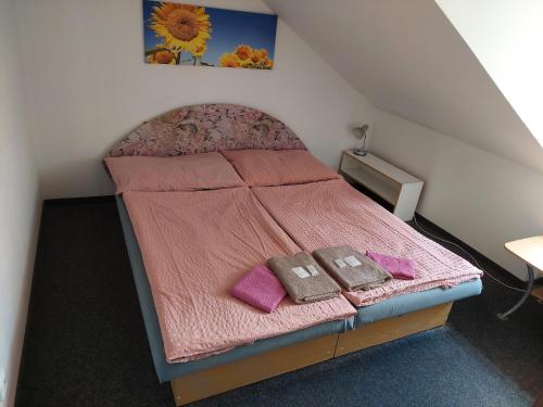 チェスキー・クルムロフにあるペンション U ソウドゥのピンクのシーツと紫の枕が付いた小さなベッド