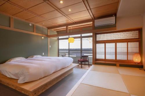 a bedroom with a large bed and a large window at Coliving & Cafe SANDO in Imabari