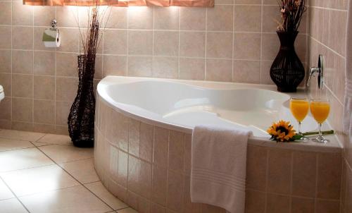 a bathroom with a tub with two glasses of orange juice at Summer Garden Guest House (The Flower Box) in Benoni