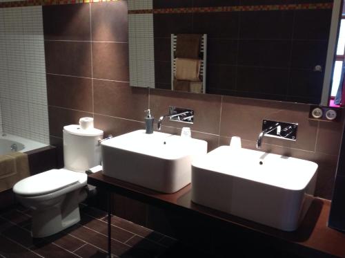 a bathroom with two sinks and a toilet and a mirror at Hôtel La Gibecière in Lohéac