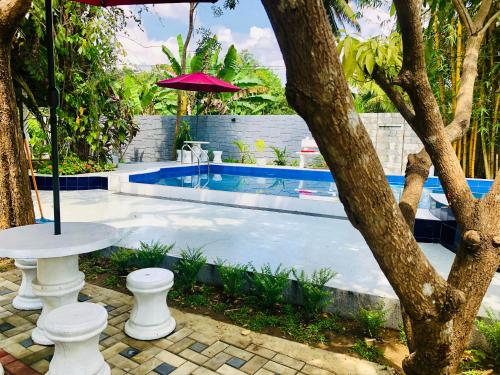 a swimming pool with a table and an umbrella at Bangalawa Resort in Habarana