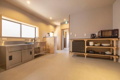 a large kitchen with a sink and a refrigerator at Coliving & Cafe SANDO in Imabari