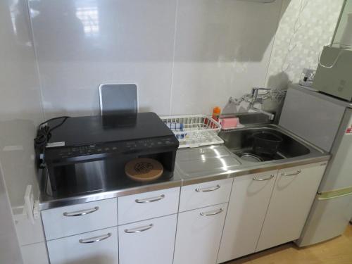 a small kitchen with a sink and a stove at Sapporo Guest House Nariya in Sapporo