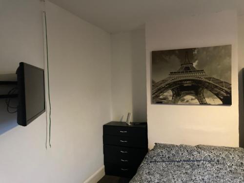 a bedroom with a bed and a picture of the eiffel tower at Trevor And The Cats in Mansfield