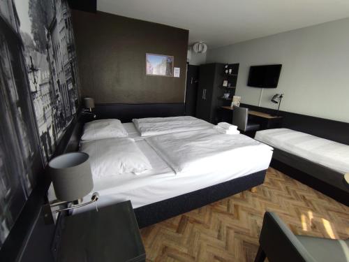 a bedroom with a large white bed and a television at Akzent City-Hotel Kleve in Kleve