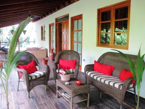 a porch with wicker chairs and red pillows at Hotel Iguanito in Santa Catalina