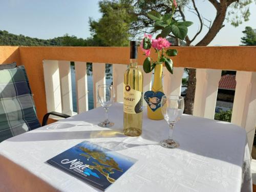 a table with a bottle of wine and two glasses at Apartments Vinko in Sobra