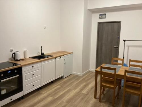 a kitchen with white cabinets and a table with chairs at Apartament Centrum Szczytno I in Szczytno
