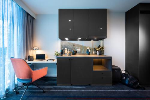 a kitchen with an orange chair and a desk at Novotel Melbourne Preston in Melbourne