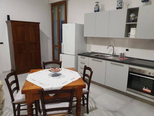 een keuken met een tafel en stoelen en een keuken met witte apparatuur bij TIZY HOUSE - appartamento ammobiliato IMOLA in Imola