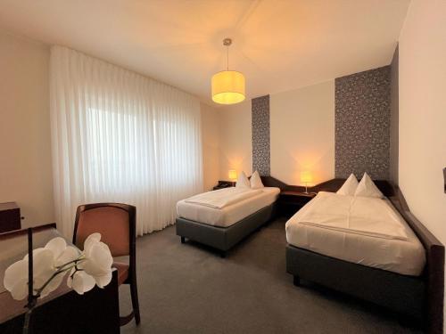 Habitación de hotel con 2 camas y mesa en Hotel Garni Geisler, en Colonia